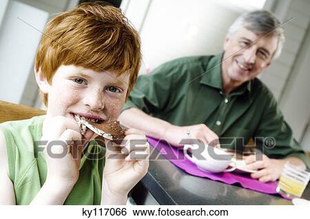 Stock Photograph - Senior man and boy having breakfast. Fotosearch