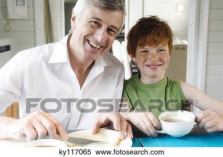 Senior man and boy having breakfast, smiling for the camera View Large Photo Image Stock Photography - Senior man and boy having breakfast, smiling for the camera. Fotosearch