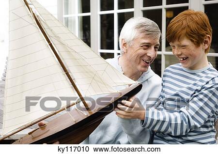 Senior man and boy holding a model boat, outdoors View Large Photo Image Stock Image - Senior man and boy holding a model boat, outdoors. Fotosearch