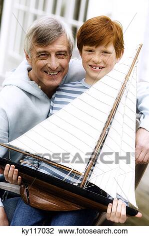 Senior man and boy holding a model boat, outdoors View Large Photo Image Stock Image - Senior man and boy holding a model boat, outdoors. Fotosearch