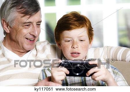Senior man and boy playing Playstation Portable View Large Photo Image Stock Image - Senior man and boy playing Playstation Portable. Fotosearch