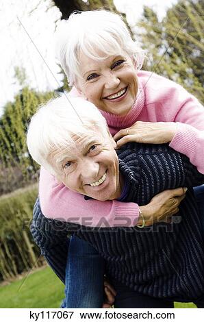 Senior man carrying senior woman on his back in garden View Large Photo Image Stock Photo - Senior man carrying senior woman on his back in garden. Fotosearch