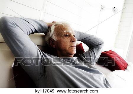 Senior man relaxing, lying on a bed View Large Photo Image Stock Photo - Senior man relaxing, lying on a bed. Fotosearch