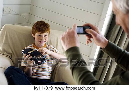 Stock Photo - Senior man taking picture of a boy with a camera phone. Fotosearch