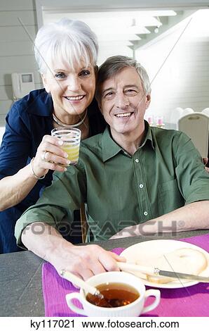 Smiling senior couple having breakfast, looking at the camera View Large Photo Image Stock Image - Smiling senior couple having breakfast, looking at the camera. Fotosearch