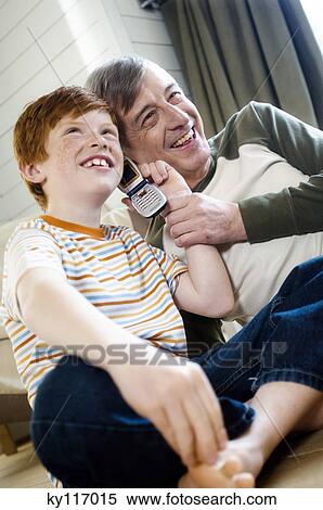Smiling senior man and boy using a mobile phone View Large Photo Image Stock Photography - Smiling senior man and boy using a mobile phone. Fotosearch