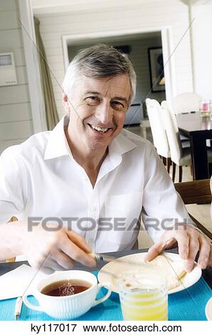 Smiling senior man having breakfast View Large Photo Image Stock Photo - Smiling senior man having breakfast. Fotosearch