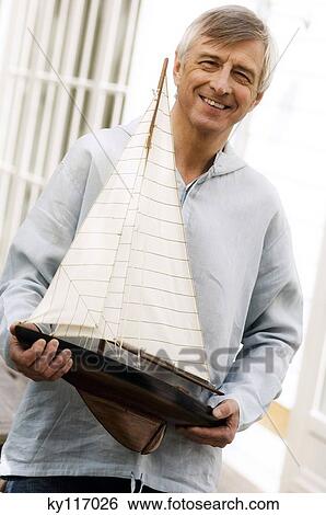 Smiling senior man holding a model boat outdoors View Large Photo Image Stock Photograph - Smiling senior man holding a model boat outdoors. Fotosearch
