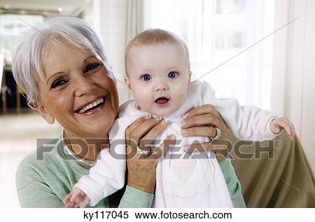 Stock Photography - Smiling senior woman holding baby girl. Fotosearch
