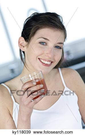 Portrait of a young smiling woman holding a glass of fruit juice View Large Photo Image Stock Photo - Portrait of a young smiling woman holding a glass of fruit juice. Fotosearch