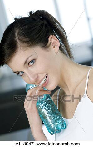 Portrait of a young smiling woman holding a mineral water bottle View Large Photo Image Stock Photo - Portrait of a young smiling woman holding a mineral water bottle. Fotosearch