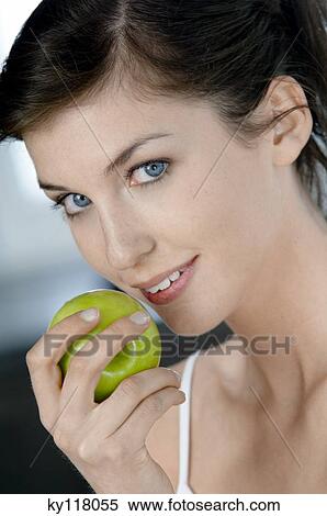 Portrait of a young woman eating an apple View Large Photo Image Stock Photography - Portrait of a young woman eating an apple. Fotosearch