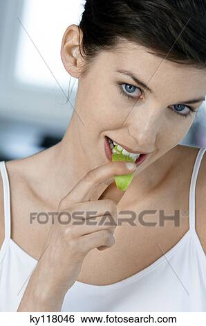 Portrait of a young woman eating apple slice View Large Photo Image Stock Photograph - Portrait of a young woman eating apple slice. Fotosearch
