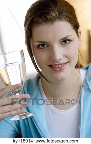 Portrait of a young woman holding a glass of water View Large Photo Image Picture - Portrait of a young woman holding a glass of water. Fotosearch