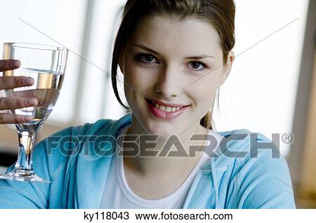 Portrait of a young woman holding a glass of water View Large Photo Image Stock Image - Portrait of a young woman holding a glass of water. Fotosearch