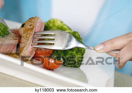 Woman eating meat with a fork, close-up View Large Photo Image Stock Image - Woman eating meat with a fork, close-up. Fotosearch