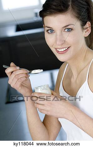 Young woman eating a plain yogurt View Large Photo Image Picture - Young woman eating a plain yogurt. Fotosearch