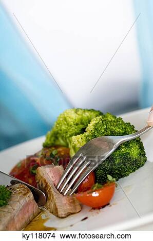 Young woman eating meat and vegetables, close-up View Large Photo Image Picture - Young woman eating meat and vegetables, close-up. Fotosearch