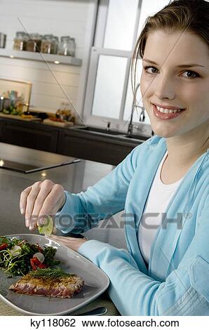 Stock Image - Young woman eating meat and vegetables. Fotosearch