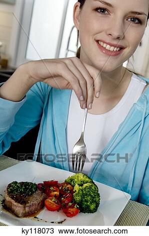 Young woman eating meat and vegetables View Large Photo Image Stock Image - Young woman eating meat and vegetables. Fotosearch