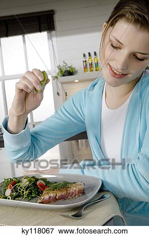 Stock Photo - Young woman eating meat and vegetables. Fotosearch
