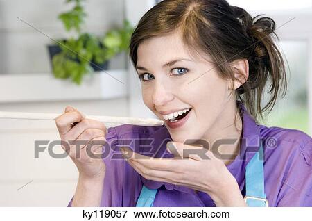 Portrait of a young smiling woman tasting food View Large Photo Image Stock Photo - Portrait of a young smiling woman tasting food. Fotosearch
