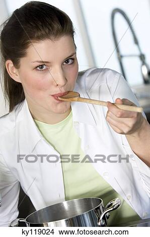 Picture - Portrait of a young woman tasting food. Fotosearch