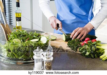 Woman making a salad, chopping cucumber, close-up View Large Photo Image Stock Photo - Woman making a salad, chopping cucumber, close-up. Fotosearch