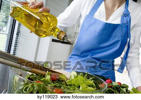 Woman pouring olive oil into a salad, close-up View Large Photo Image Stock Image - Woman pouring olive oil into a salad, close-up. Fotosearch