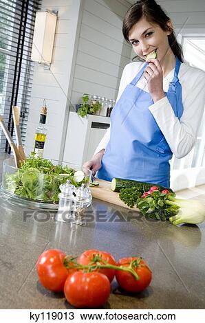 Young smiling woman cooking, tasting cucumber slice View Large Photo Image Stock Image - Young smiling woman cooking, tasting cucumber slice. Fotosearch