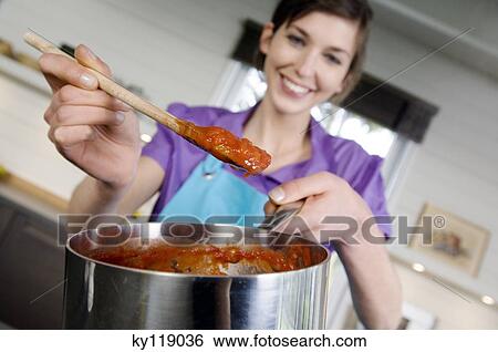 Young smiling woman cooking tomato sauce View Large Photo Image Stock Photograph - Young smiling woman cooking tomato sauce. Fotosearch