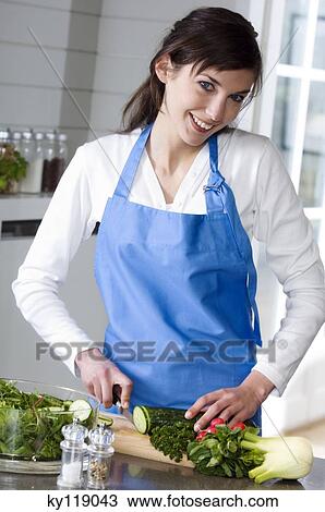 Young smiling woman making a salad, chopping cucumber View Large Photo Image Stock Image - Young smiling woman making a salad, chopping cucumber. Fotosearch