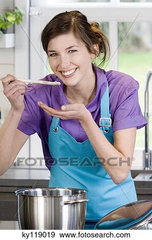 Young smiling woman tasting food View Large Photo Image Stock Photo - Young smiling woman tasting food. Fotosearch