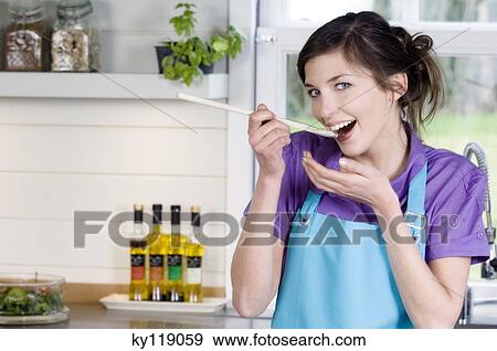 Stock Photo - Young smiling woman tasting food. Fotosearch