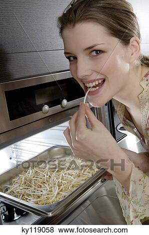 Young woman eating bean sprouts coming out of the oven View Large Photo Image Stock Photo - Young woman eating bean sprouts coming out of the oven. Fotosearch