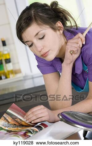 Young woman looking at a recipe book View Large Photo Image Stock Photo - Young woman looking at a recipe book. Fotosearch