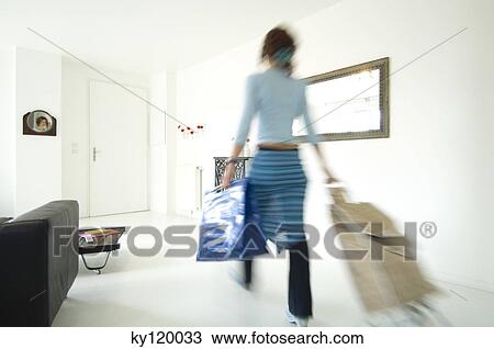 Woman carrying a bag and a shopping trolley in a living-room View Large Photo Image Stock Image - Woman carrying a bag and a shopping trolley in a living-room. Fotosearch