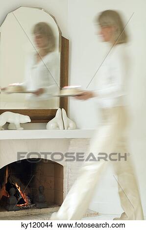 Picture - Woman carrying a birthday cake, fireplace. Fotosearch