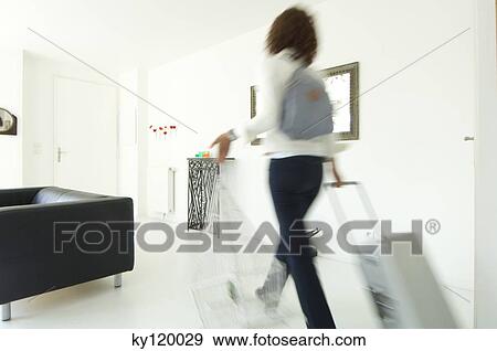 Stock Photo - Woman carrying suitcase and birdcage in a living-room. Fotosearch