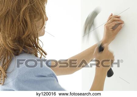 Woman hammering a nail View Large Photo Image Stock Photograph - Woman hammering a nail. Fotosearch
