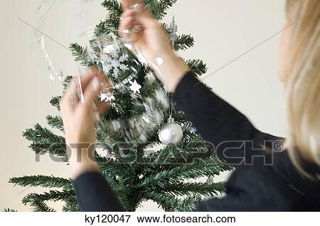 Woman hanging decoration on Christmas tree, close-up View Large Photo Image Stock Photo - Woman hanging decoration on Christmas tree, close-up. Fotosearch