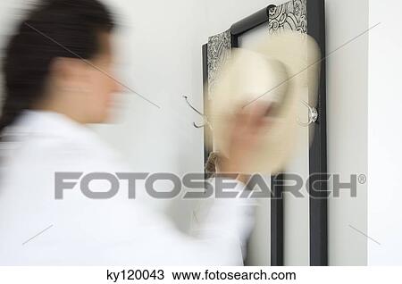 Stock Image - Woman hanging hat, close-up. Fotosearch