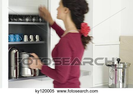 Woman holding a kettle in the kitchen View Large Photo Image Stock Photography - Woman holding a kettle in the kitchen. Fotosearch