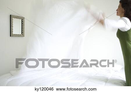 Woman making a bed View Large Photo Image Stock Photograph - Woman making a bed. Fotosearch