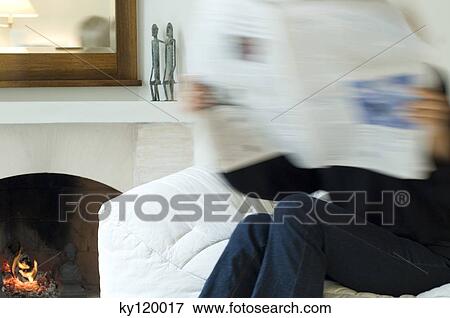 Stock Photo - Woman reading newspaper by the fireplace. Fotosearch