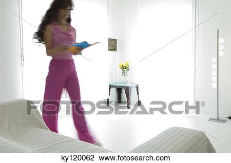 Woman reading, standing in a living-room View Large Photo Image Stock Image - Woman reading, standing in a living-room. Fotosearch