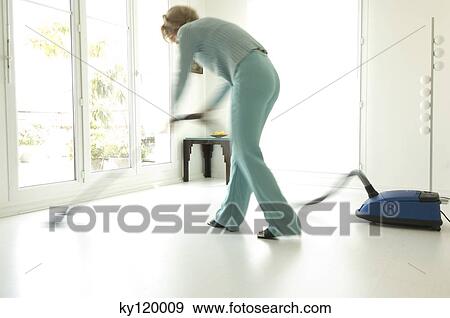 Woman vacuuming in living-room View Large Photo Image Stock Photo - Woman vacuuming in living-room. Fotosearch