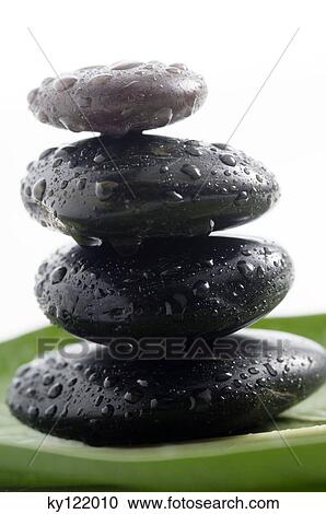 Stock Image - 4 peebles and waterdrops, close-up. Fotosearch