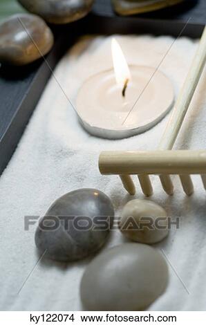 Picture - Candle, peebles and rake in zen garden, close-up. Fotosearch