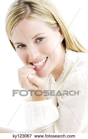 Stock Photo - Portrait of a young woman biting her nails, indoors (studio). Fotosearch